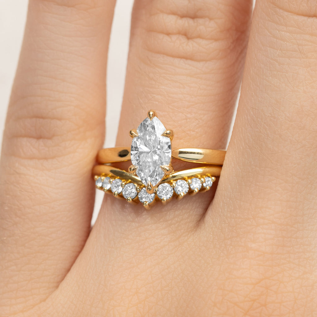 A Canadian-made bridal set with a marquise diamond engagement ring and v-shaped wedding ring in 18K yellow gold.