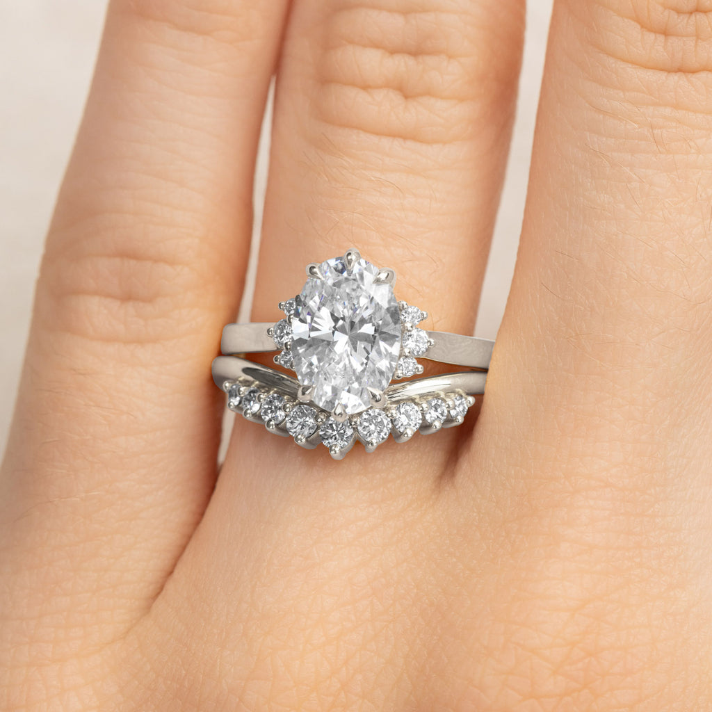 A Canadian-made bridal set with an oval halo diamond engagement ring and a curved diamond wedding ring in 18K white gold.