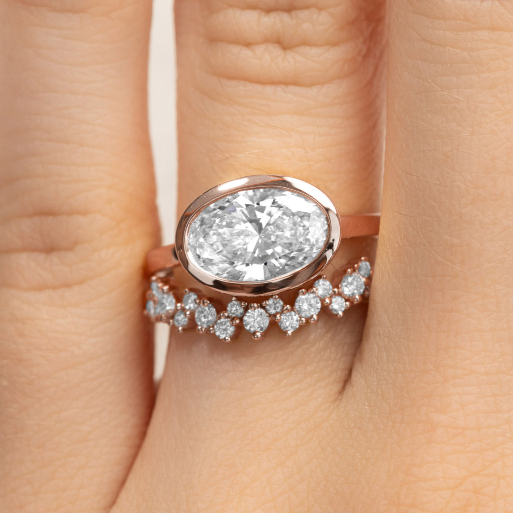 Bezel-set oval diamond engagement ring stacked with a diamond wedding band. Canadian-made bridal set in 14K rose gold.