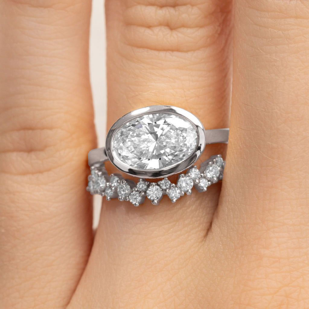 Canadian-made bridal set with a bezel oval diamond engagement ring and curved wedding ring in 18K white gold.