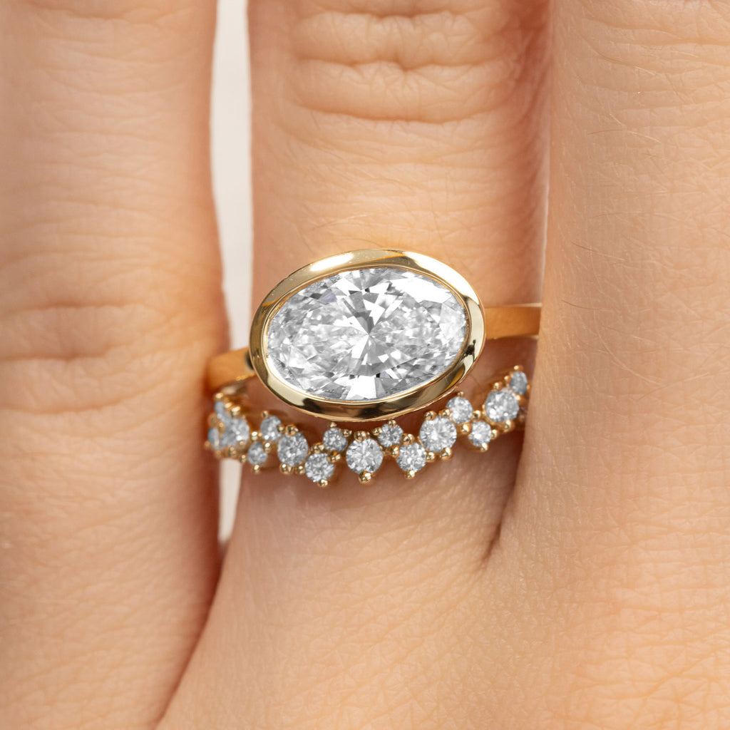 Bezel-set oval diamond engagement ring and matching wedding ring in 18K yellow gold. Canadian-made.