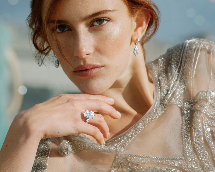 Model wearing canadian-made 18k white gold oval diamond engagement ring with pave band paired with marquise diamond dangle earrings